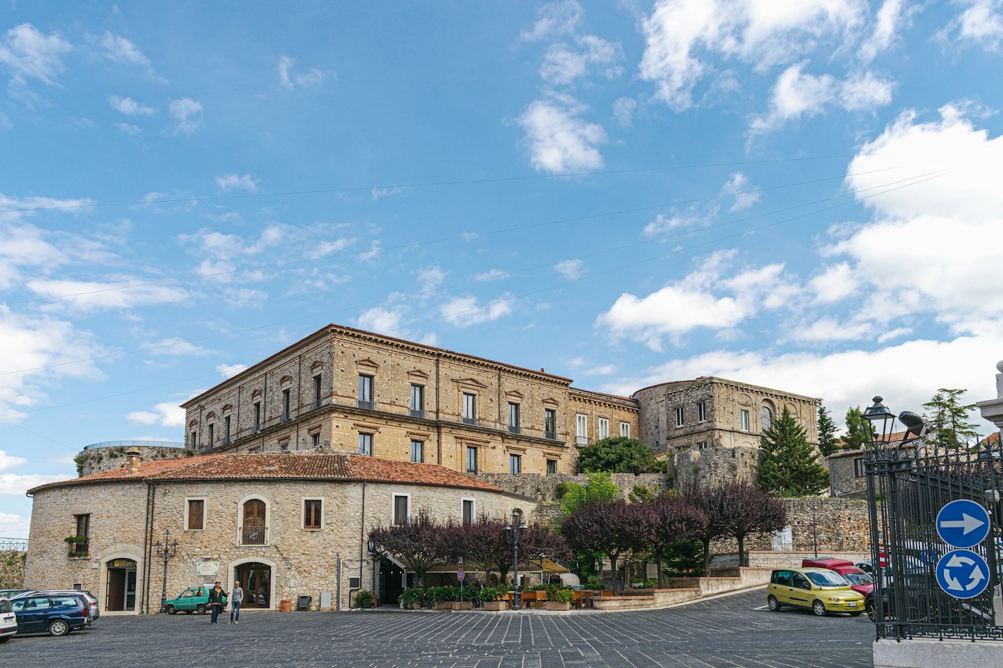 Piazza di città europea con edifici in pietra e tetti rossi.