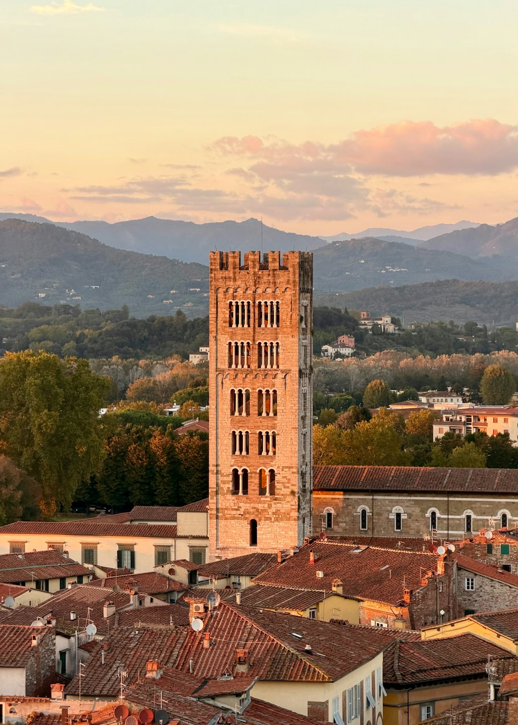 Un campanile storico in pietra si erge sopra un paese di tetti in cotto.