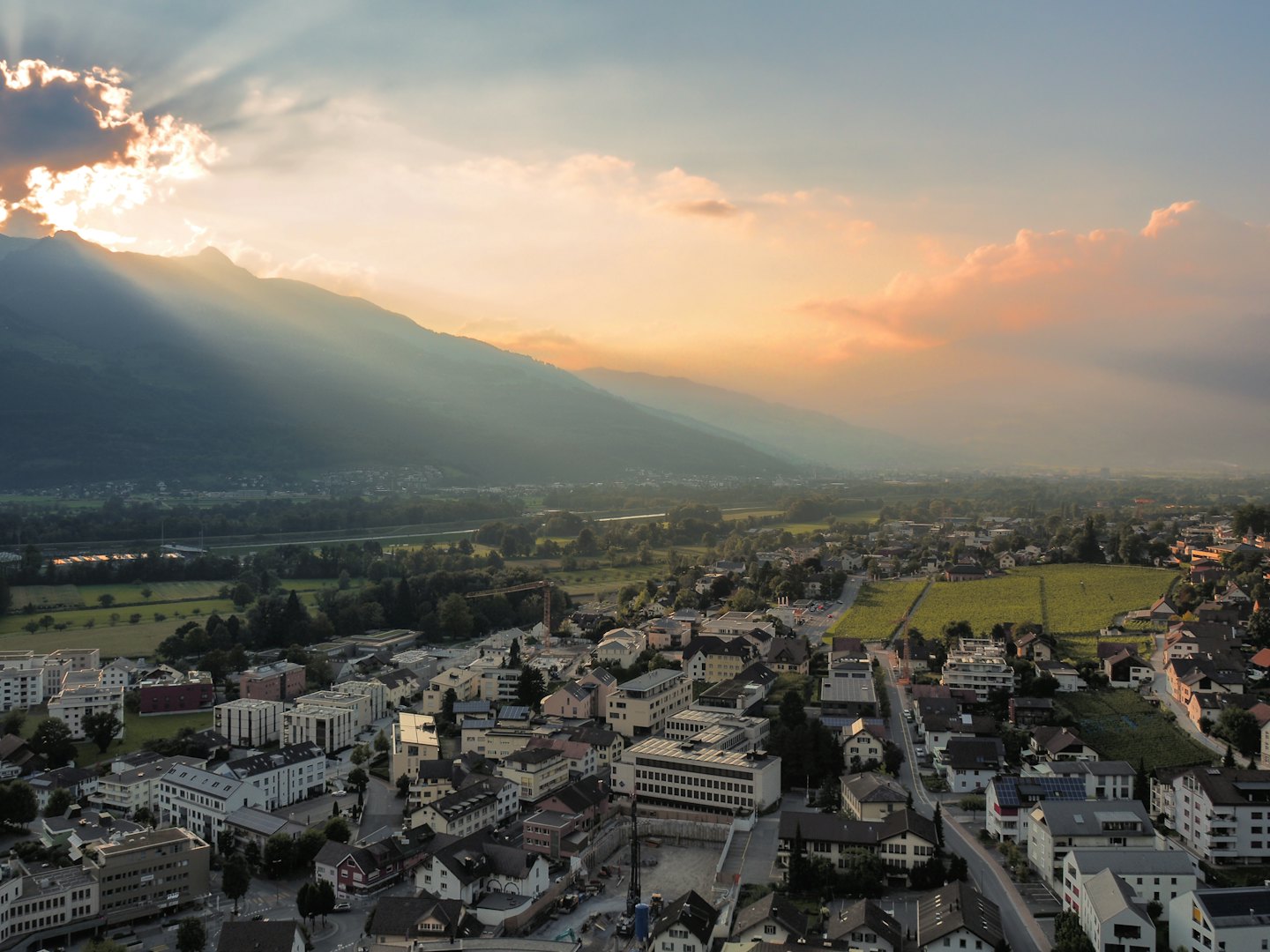 Paese in una valle montana con vigneti al tramonto.